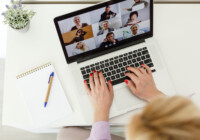 Cropped image of young female student attending online lecture on laptop at desk