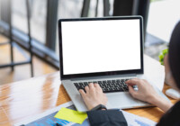 Close-up of a businesswoman working on a laptop blank white screen at office. Mock up.